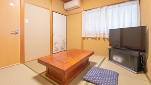 A traditional Japanese room with tatami flooring, a low wooden table, a television, and sliding doors. - The EXP Yachiyo (Uda)