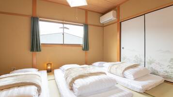 A traditional Japanese room with tatami flooring, two beds with white bedding, a shoji screen, and a hanging lantern.