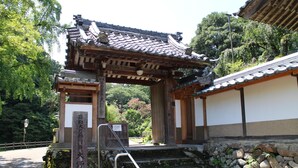 A traditional Japanese gate with a tiled roof and wooden structure, leading to a stone staircase. - The EXP Yachiyo (Uda)
