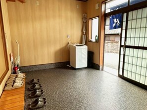A room with a wooden floor, a white heater, a guitar, and a traditional Japanese sliding door. - The EXP Yachiyo (Uda)