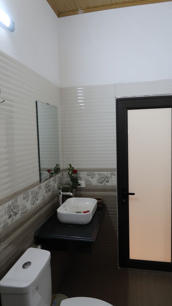 A bathroom with a white sink, a mirror, a toilet, and a door. - Tam Coc Sweet Home (Nam Hoa Lu)