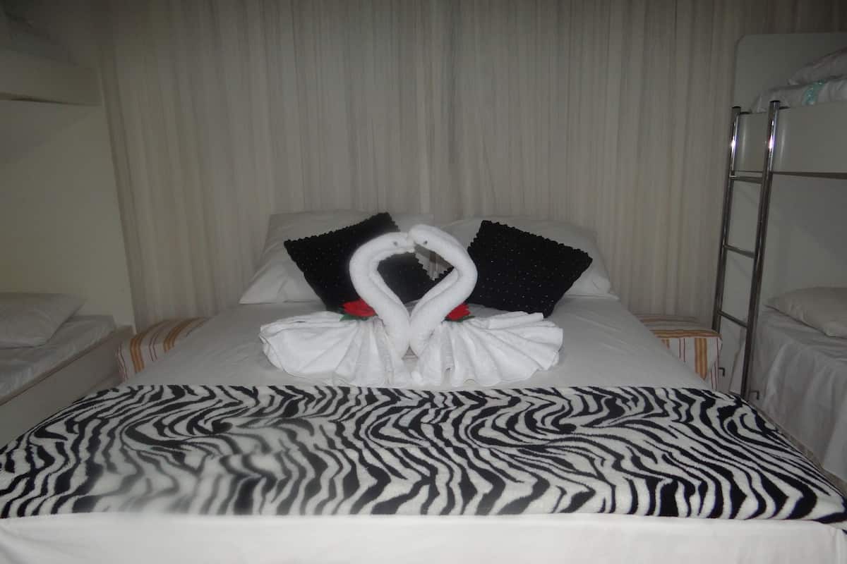 A hotel room with a bed featuring a zebra-patterned bedspread, a white swan-shaped towel arrangement, and black and white pillows.