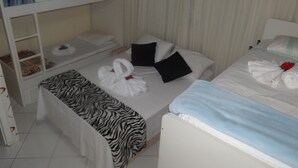 Et hotelværelse med køjeseng, et lille skrivebord med lampe, pænt redte senge med håndklæder og puder, samt et sengetæppe med zebra-mønster.