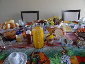 A breakfast table with various food items, drinks, and condiments. - Casa Temporada Jardim Iguaçu (Foz do Iguaçu)
