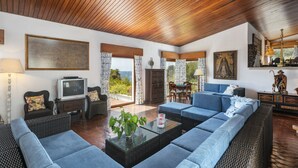 A spacious living area with a large sofa, a television, and a dining table with chairs. - Villa Quinta da Marinha (Carvoeiro)