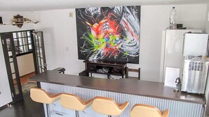 Una cocina moderna con barra, un cuadro abstracto de gran tamaño y un refrigerador.