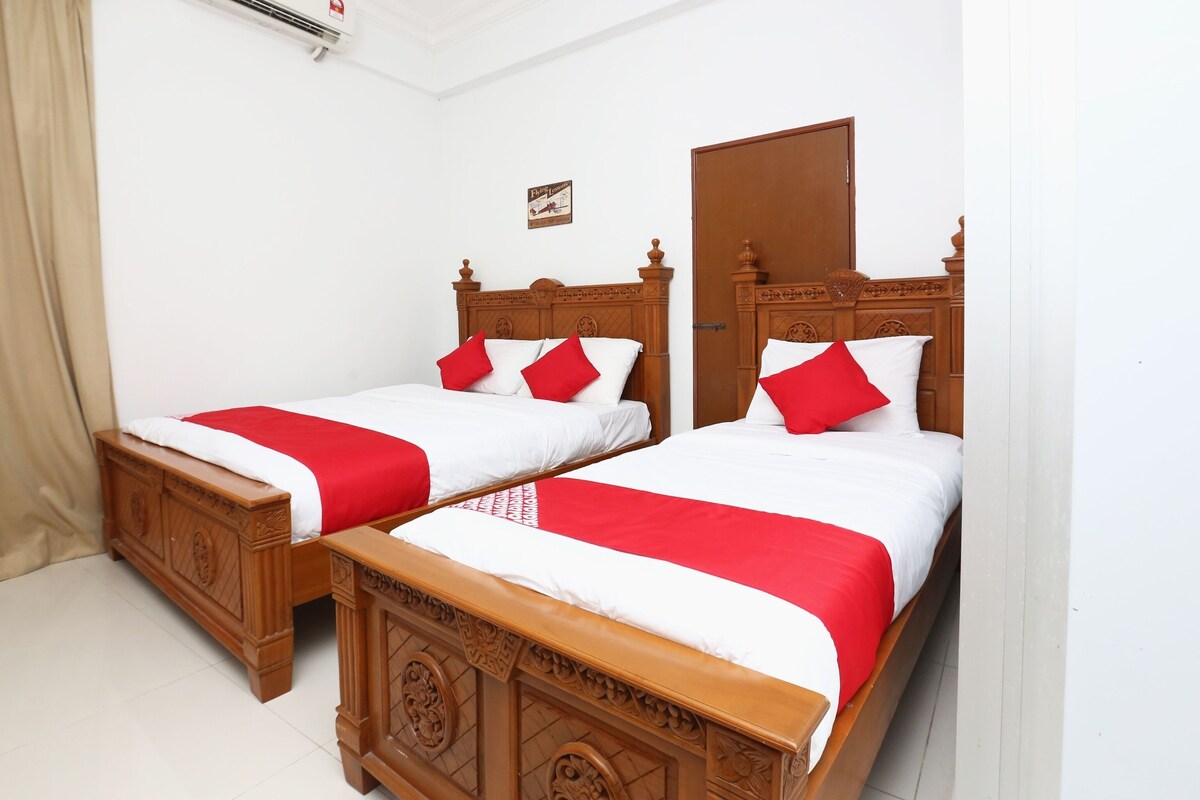 A hotel room with two wooden beds, each with a red and white bedspread and matching pillows.