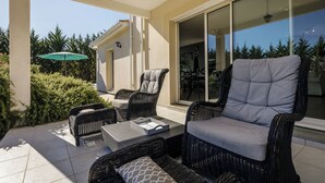 Une terrasse extérieure avec des meubles en osier, une table et un parasol vert.