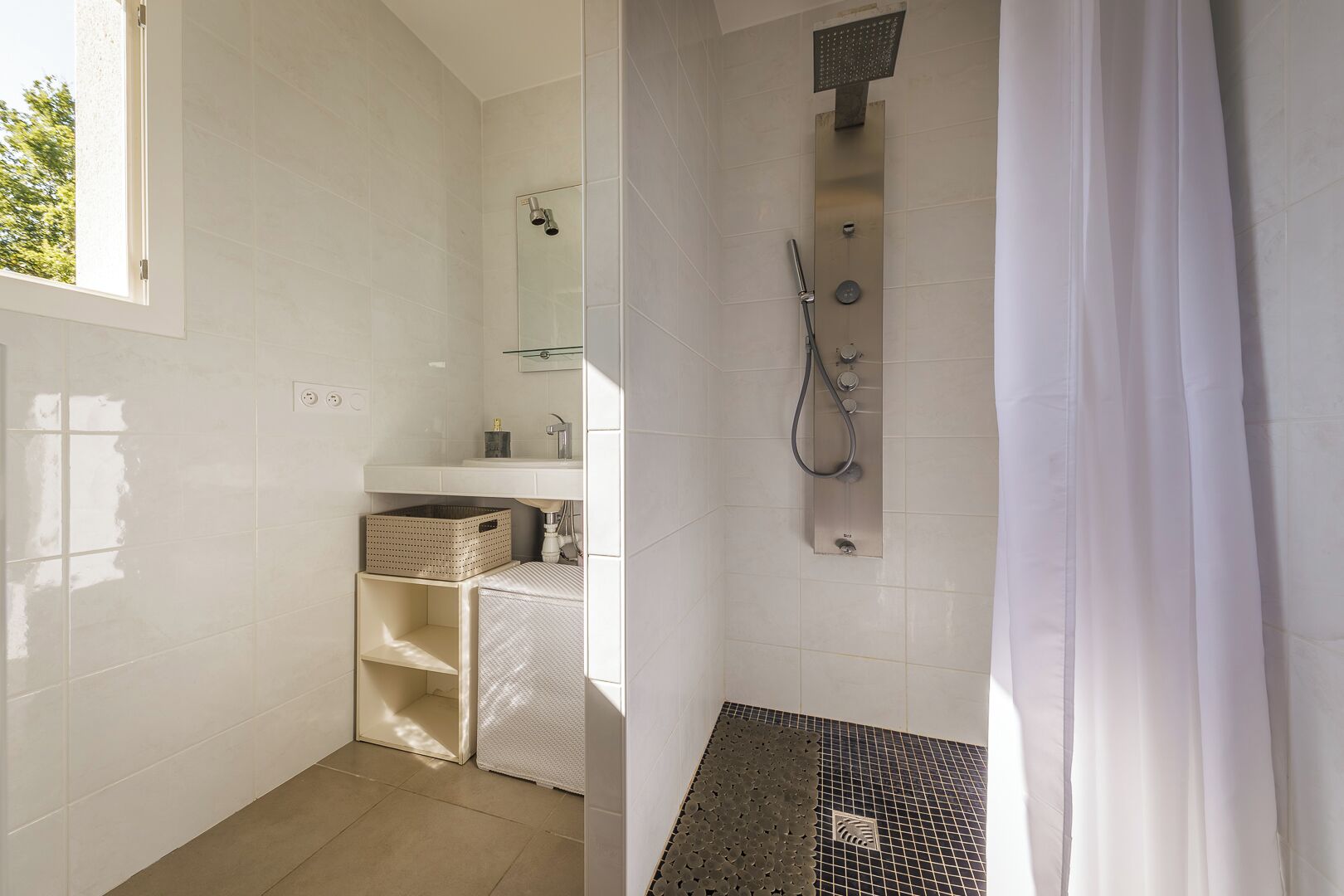 Un baño moderno con ducha, lavabo y espejo.