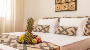 A bed with patterned pillows and a fruit plate on the side. - Villa Agave (Naxos)
