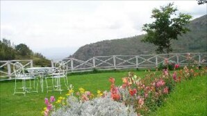 A garden with a metal fence, flowering plants, and a hill in the background. - Mystique Ville (Ootacamund)