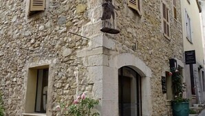 Un edificio de piedra con una pequeña entrada, un banco y una mesa roja en el exterior.