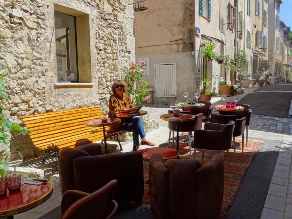 Un café en plein air avec des murs en pierre, des bancs en bois et des tables avec des chaises.