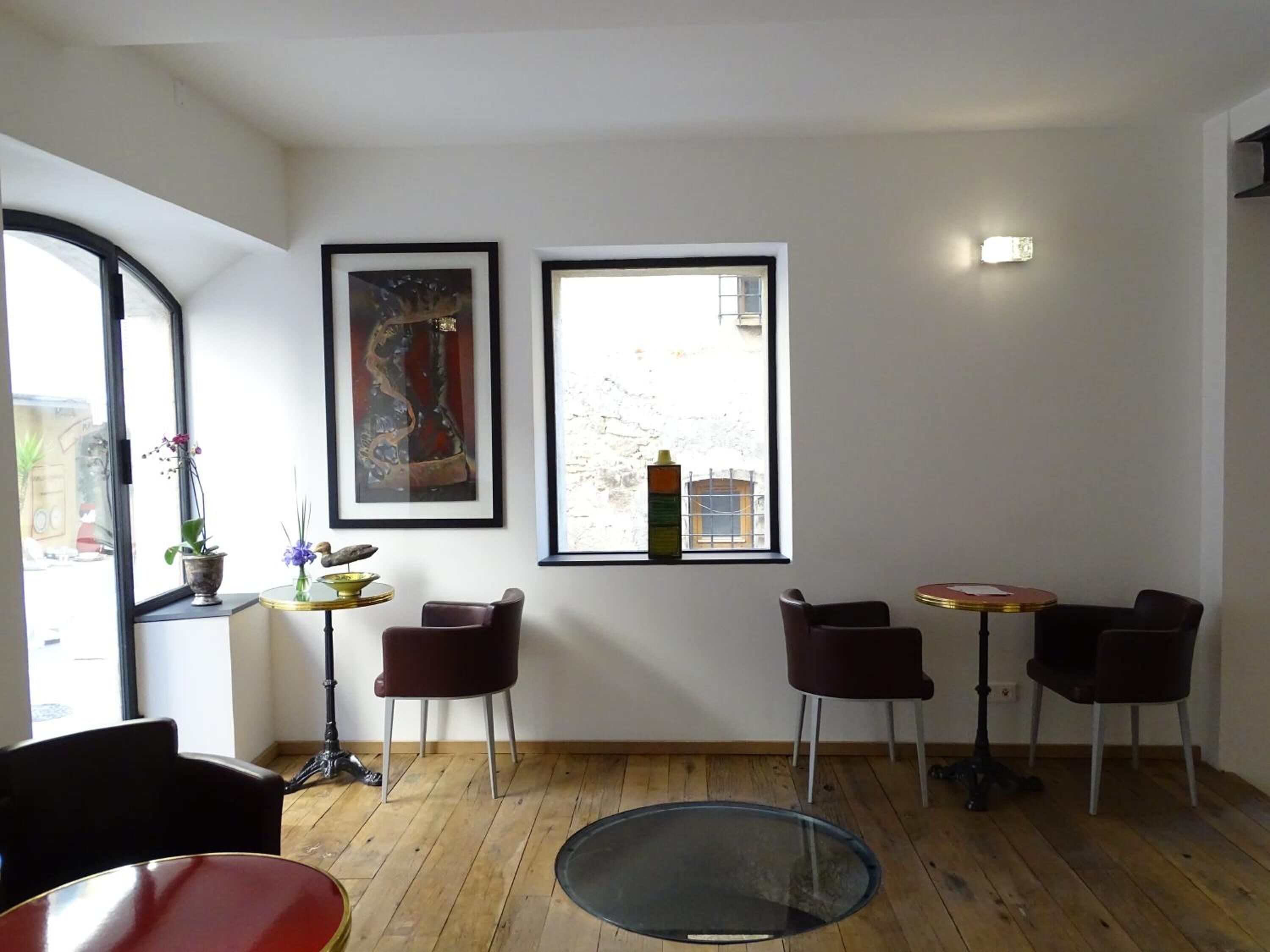 A room with a wooden floor, two windows, a table, and two chairs.