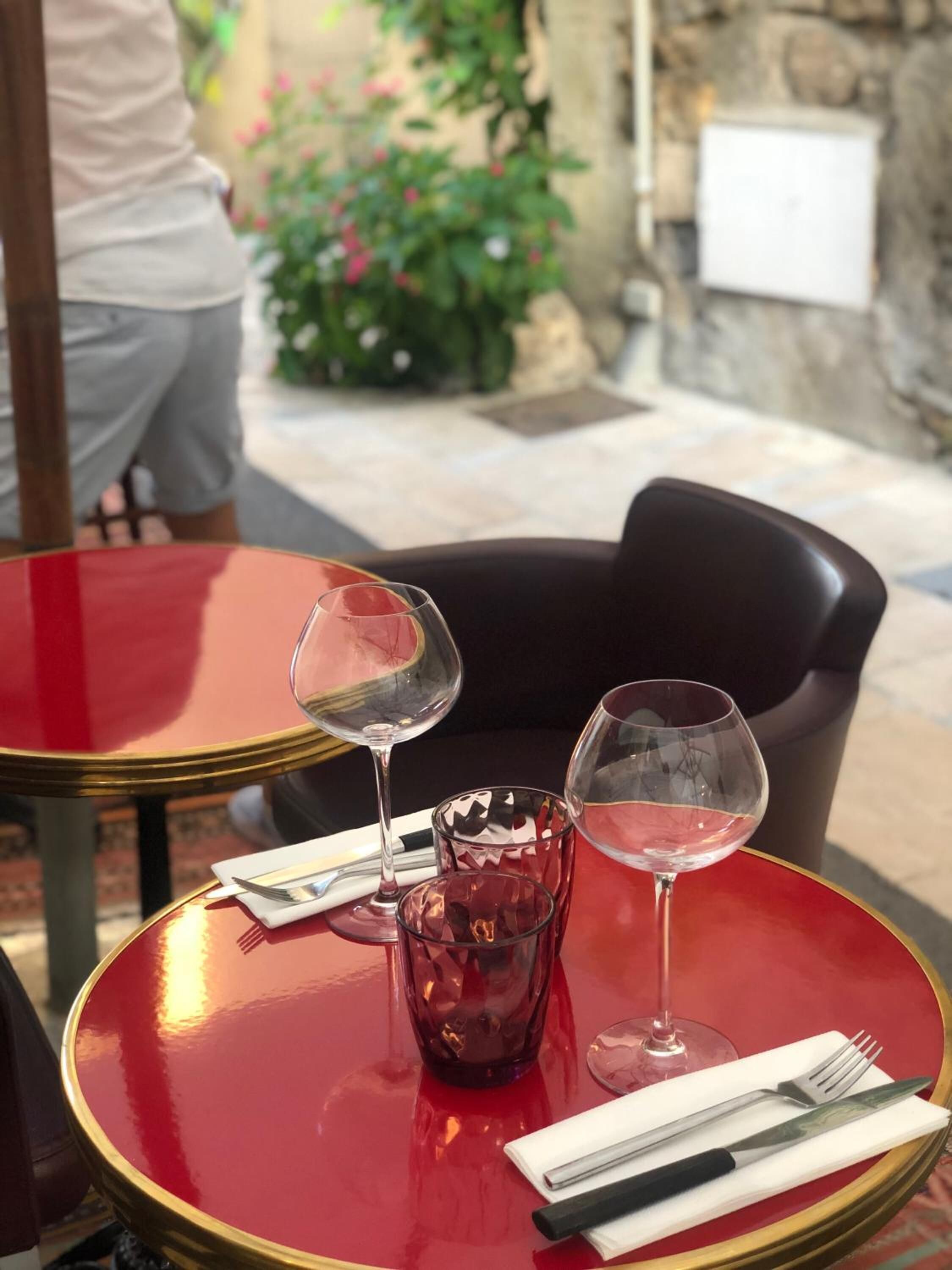 Una mesa roja con dos copas de vino y un mantel con cubiertos.