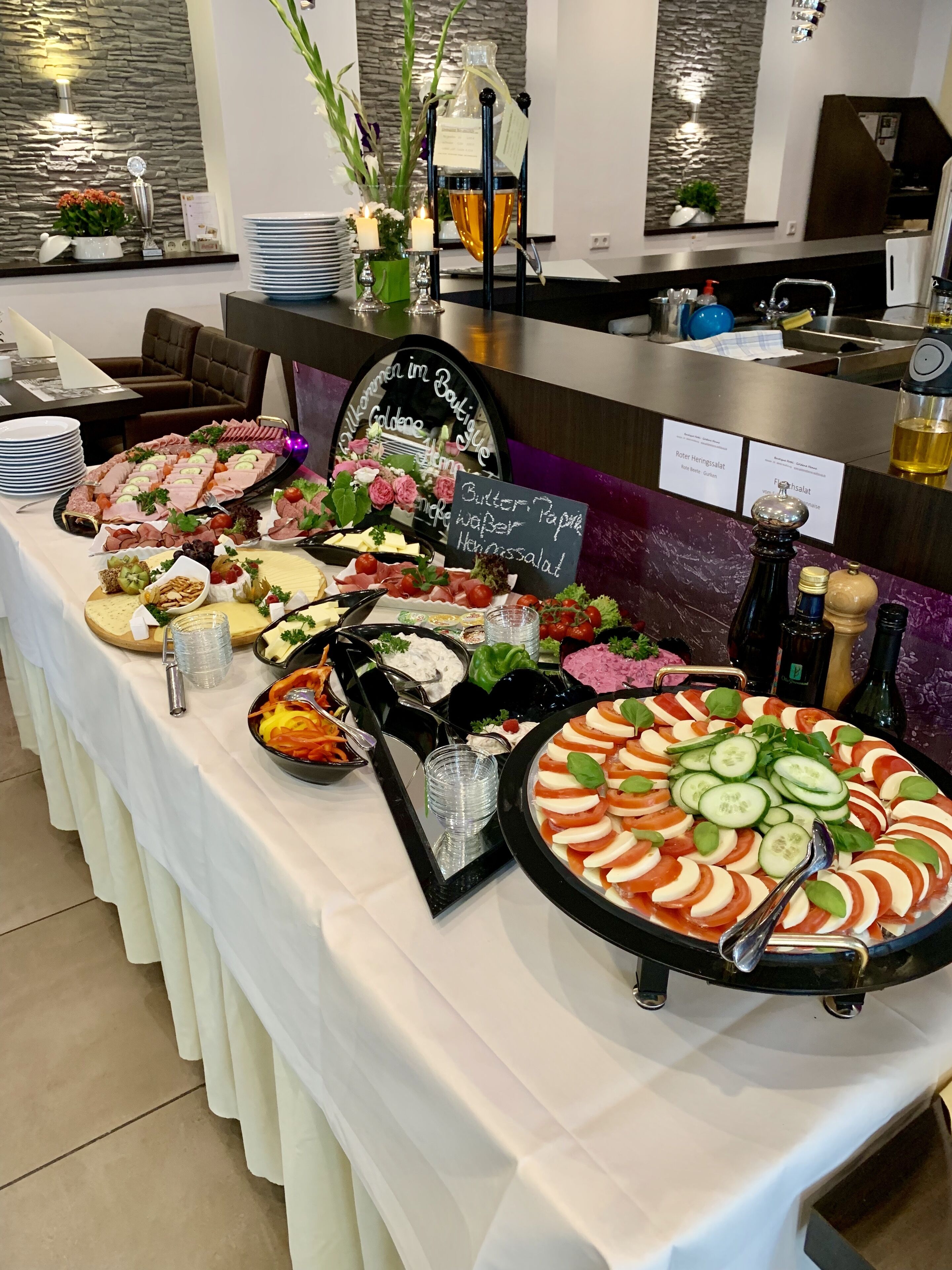 Taula de buffet amb diferents plats i un cartell que diu 'Butter, Paprika, Heringssalat'.