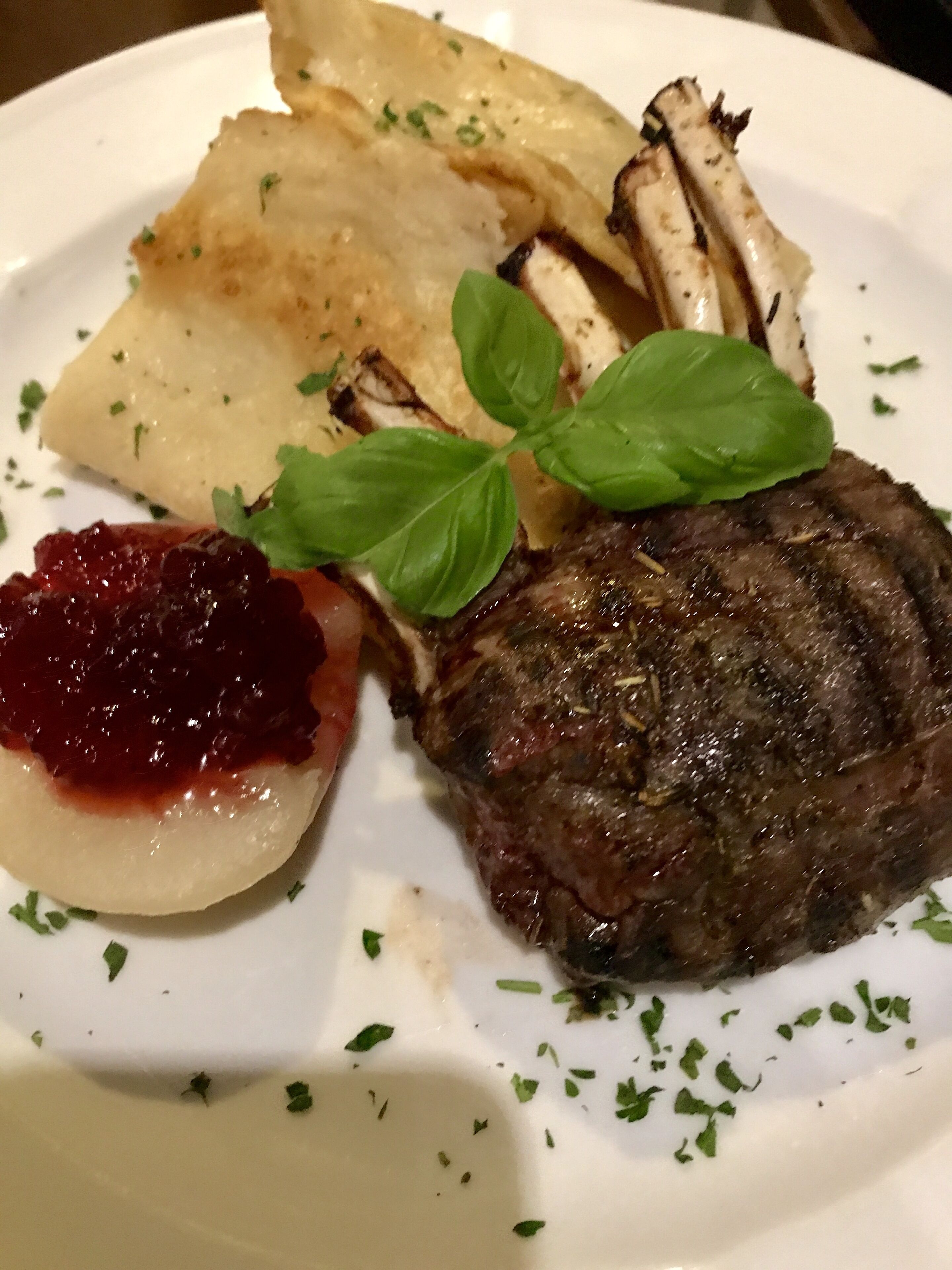 A plate with a steak, roasted potatoes, and a side of red sauce.