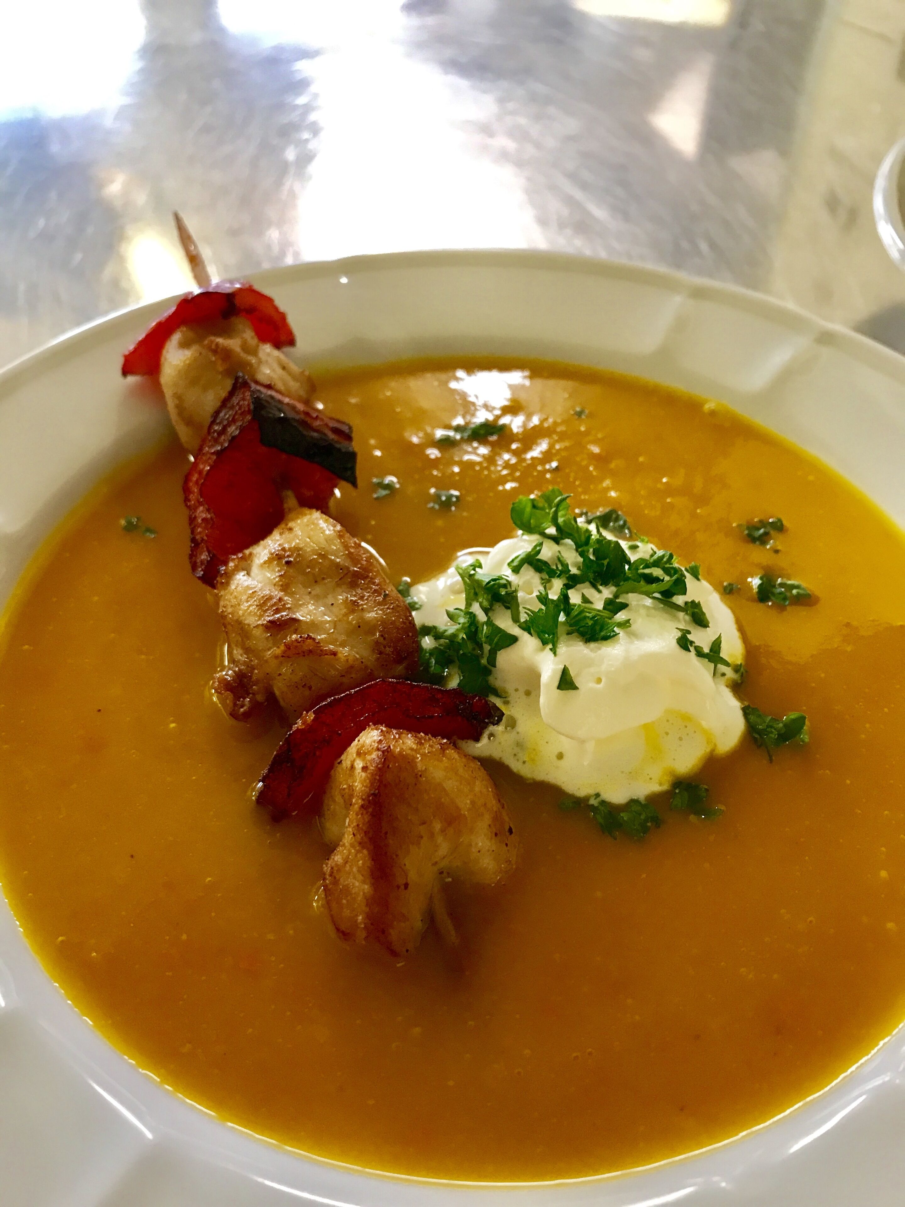 A bowl of soup with a poached egg, bacon, and herbs.