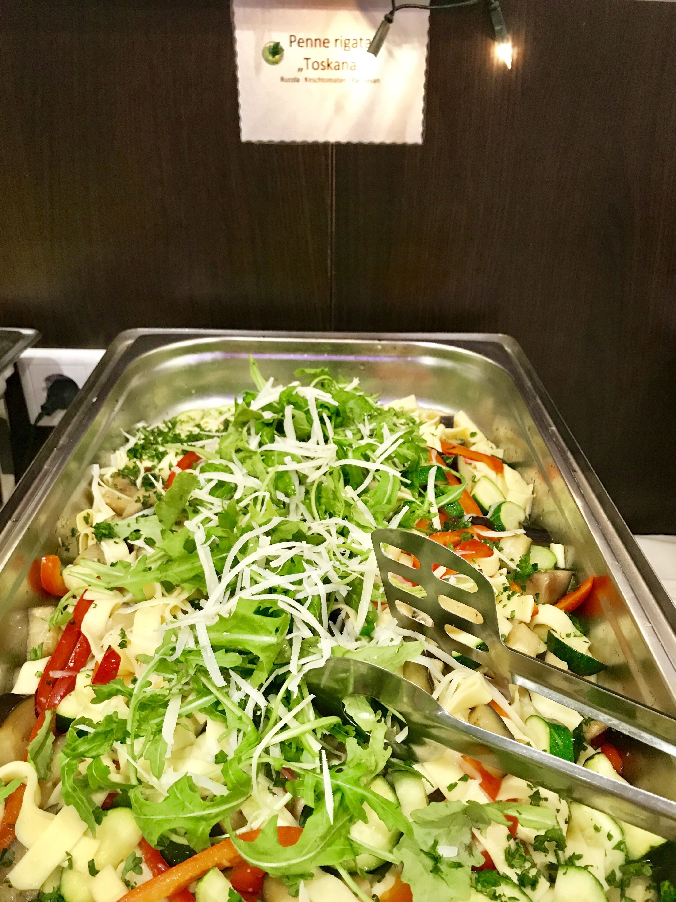 Een saladebar met diverse verse groenten en geraspte kaas.