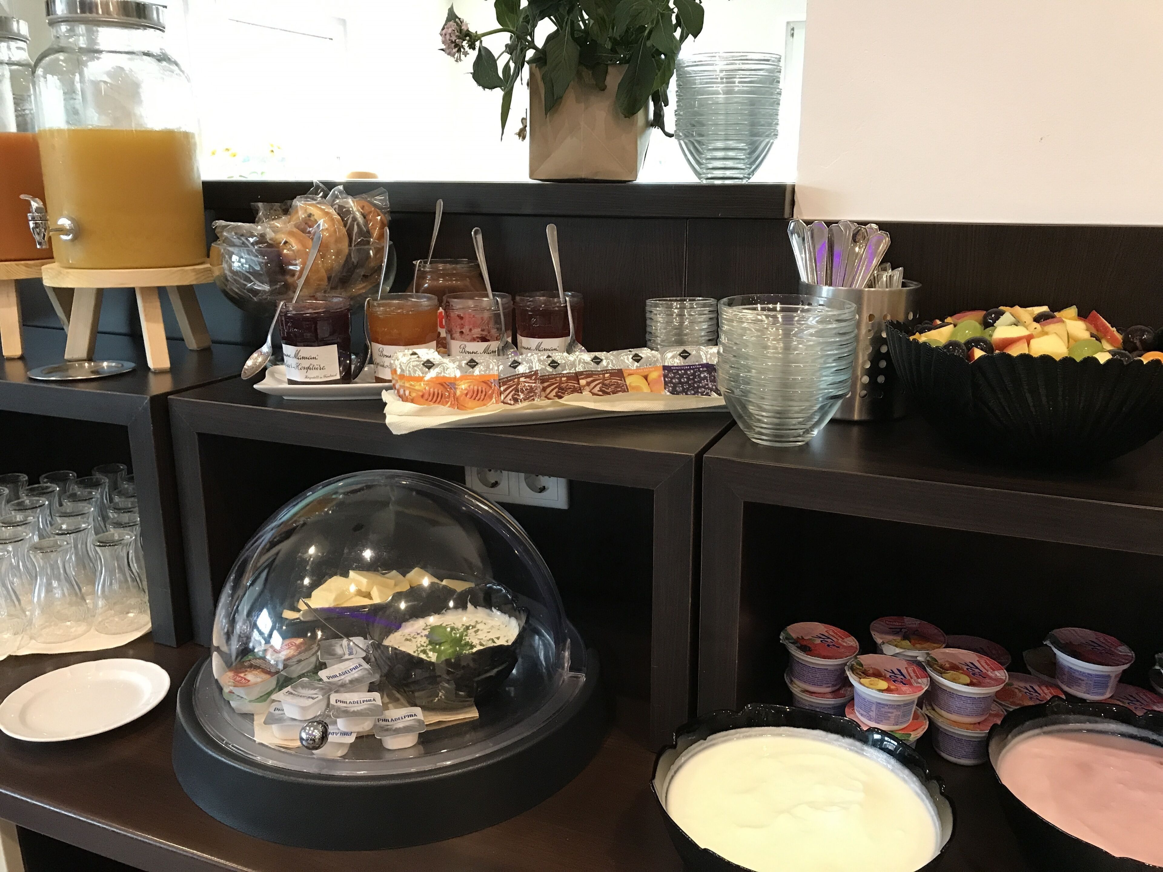 Ein reichhaltiges Buffet mit verschiedenen Speisen, darunter eine Obstschale, eine Käseplatte und eine Auswahl an Dips.