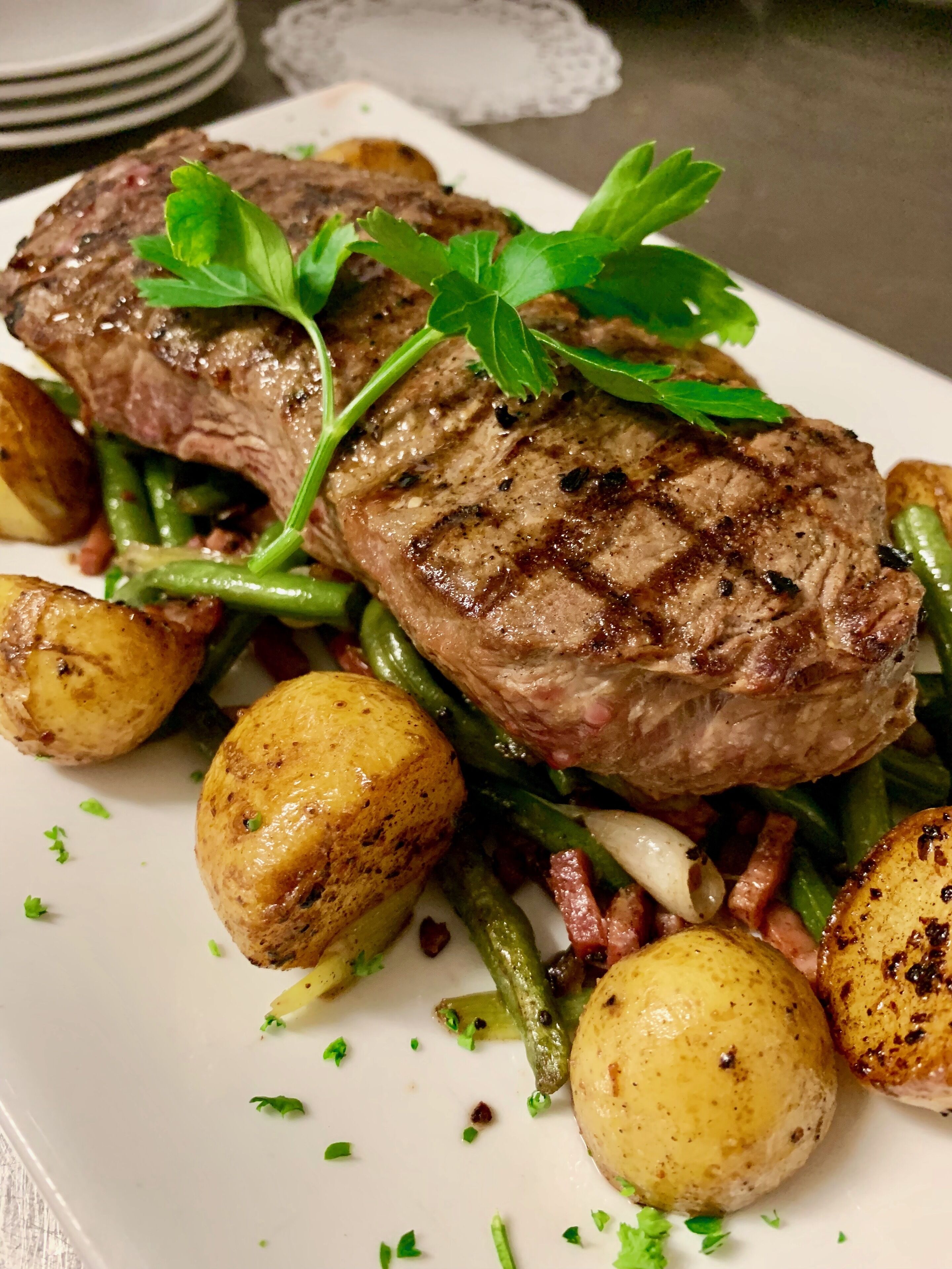 Un plato de filete a la parrilla con judías verdes y patatas asadas.