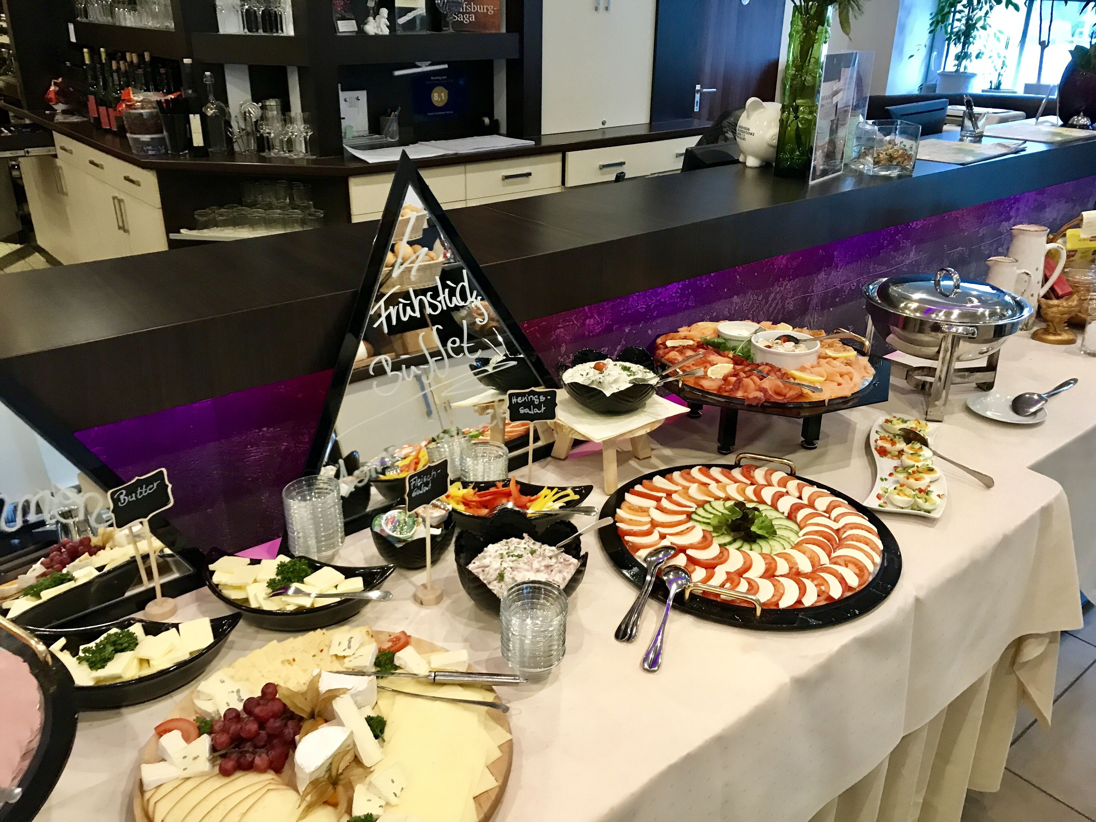 Une table de buffet proposant divers plats, notamment des fromages, des salades et un assortiment de fruits.