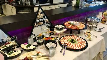 Une table de buffet proposant divers plats, notamment des fromages, des salades et un assortiment de fruits.