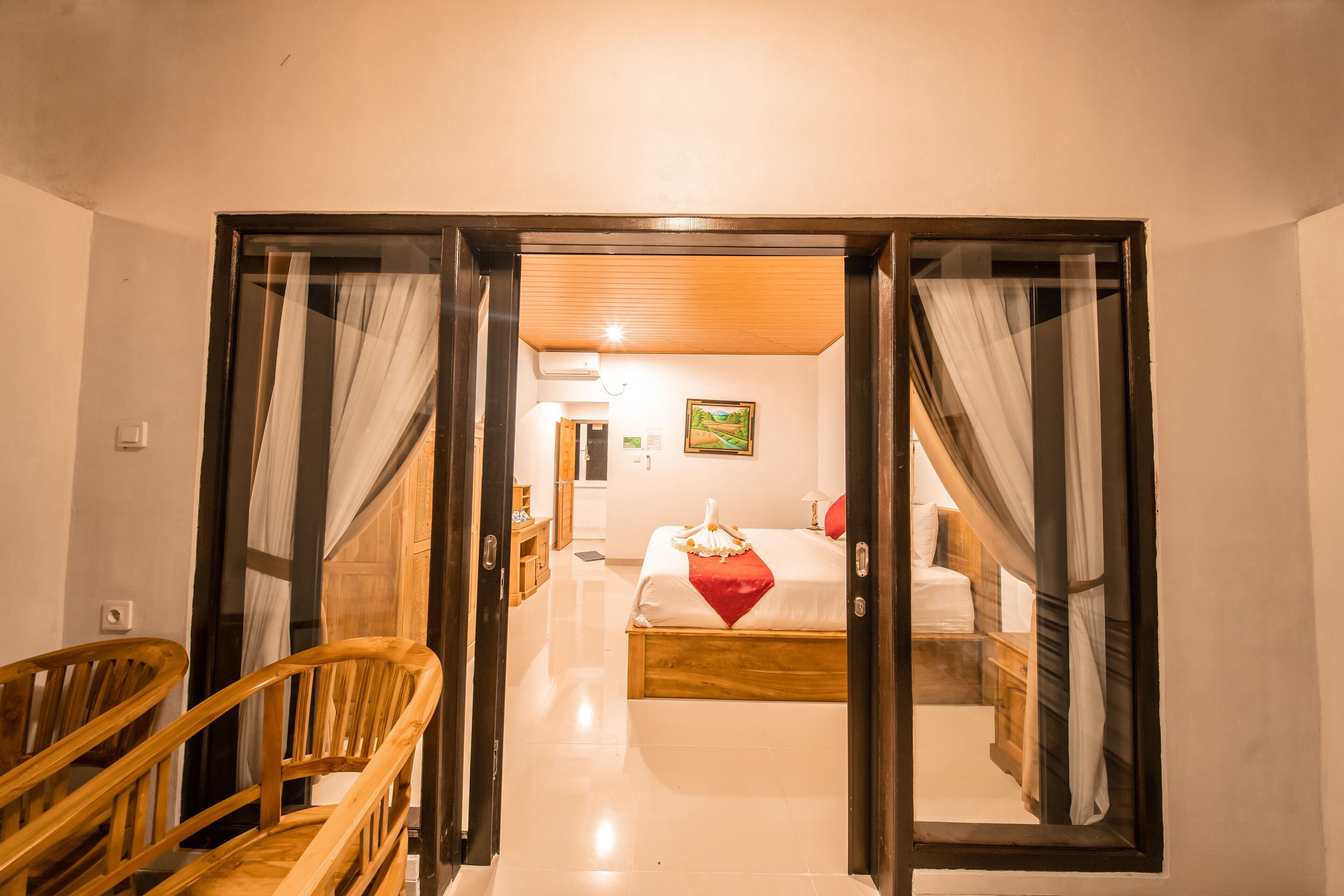 Een hotelkamer met een houten bed, een rood kussen en een houten stoel.