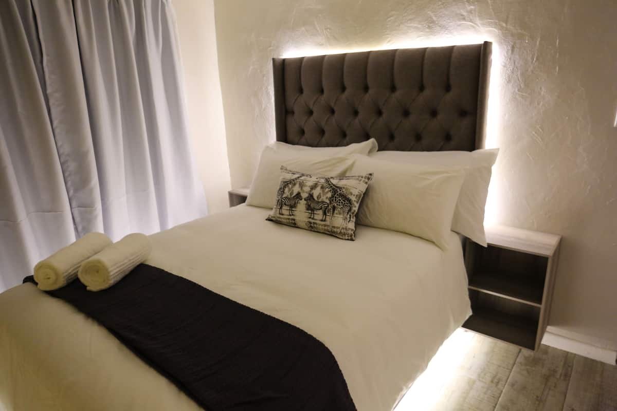 A neatly made bed with a tufted headboard, white bedding, and a black throw blanket.