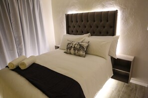 A neatly made bed with a tufted headboard, white bedding, and a black throw blanket. - Sardonyx (Cape Town)