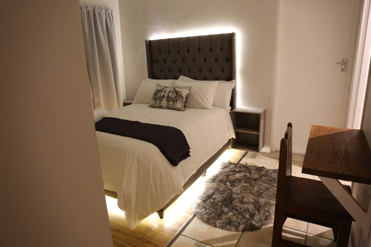 A bedroom with a bed, bedside tables, a chair, and a rug.