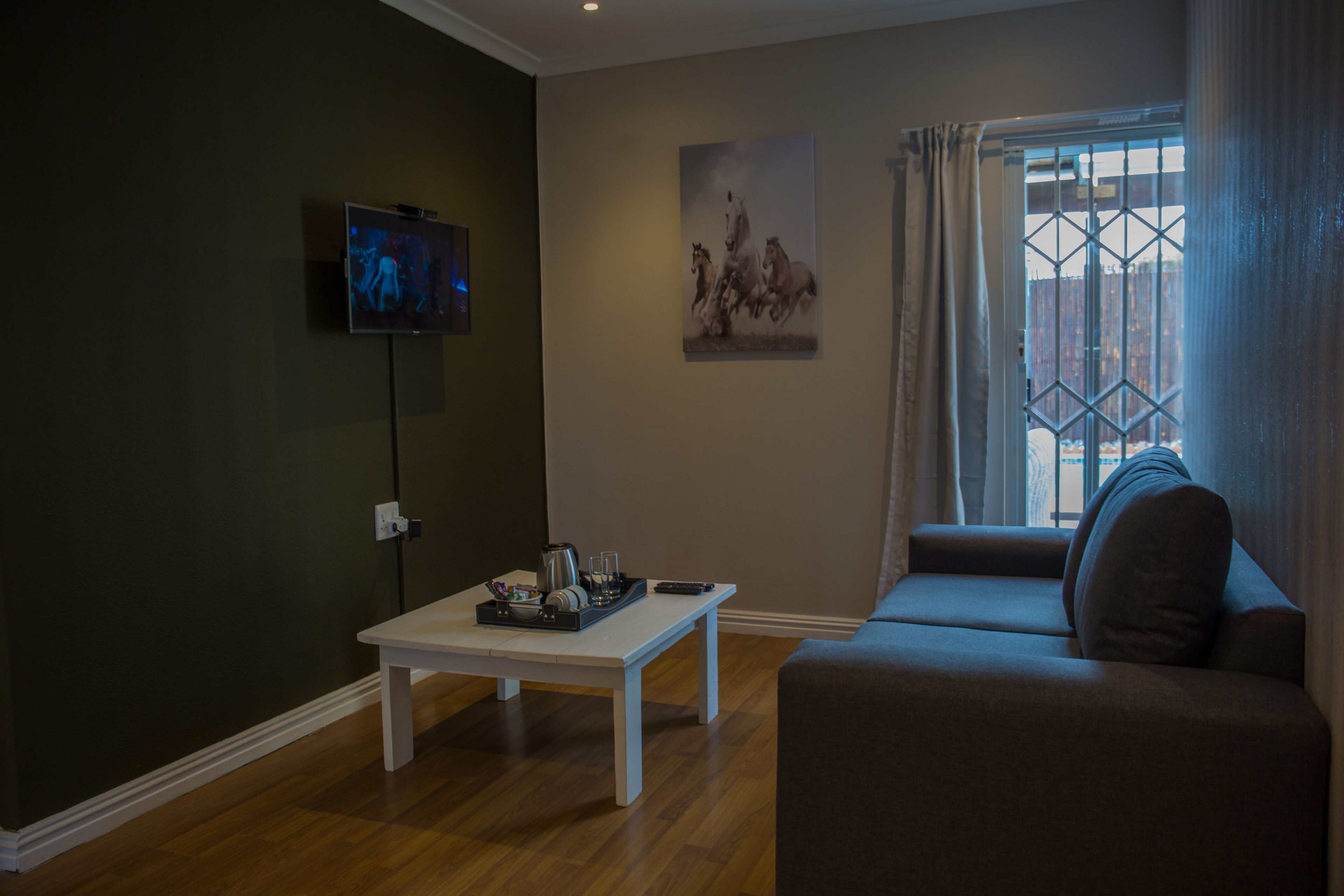 A living room with a sofa, a coffee table, a TV, and a painting on the wall.