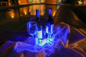 A glass table with two bottles and two wine glasses on a white cloth. - Sardonyx (Cape Town)