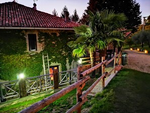 A rustic house with a red-tiled roof, a wooden fence, and a palm tree.
