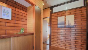 A wooden reception desk with a framed picture and a potted plant. - Yoshimura House Hotel 6 (Fujikawaguchiko)
