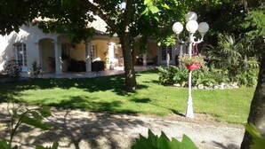 A courtyard with a white building, a tree, and a street lamp. - Le Cabassou (Begadan)