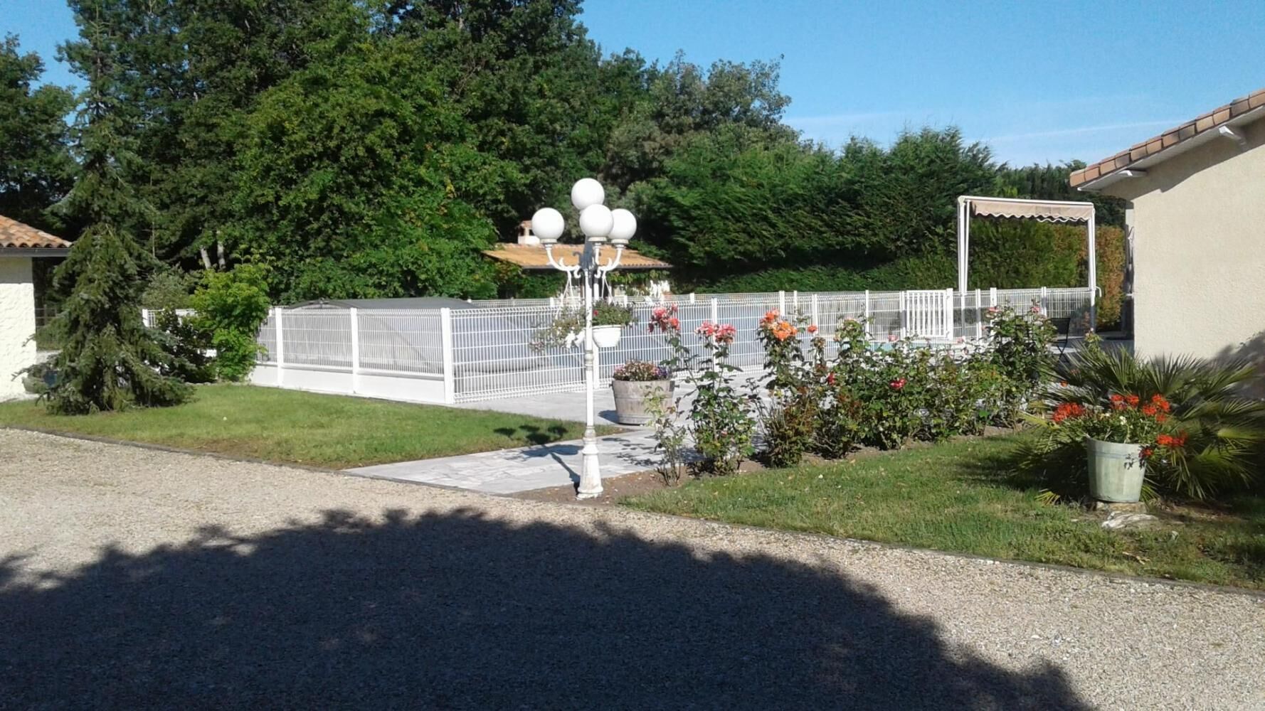 A residential property with a fenced garden, a lamp post, and a small pathway leading to a house.