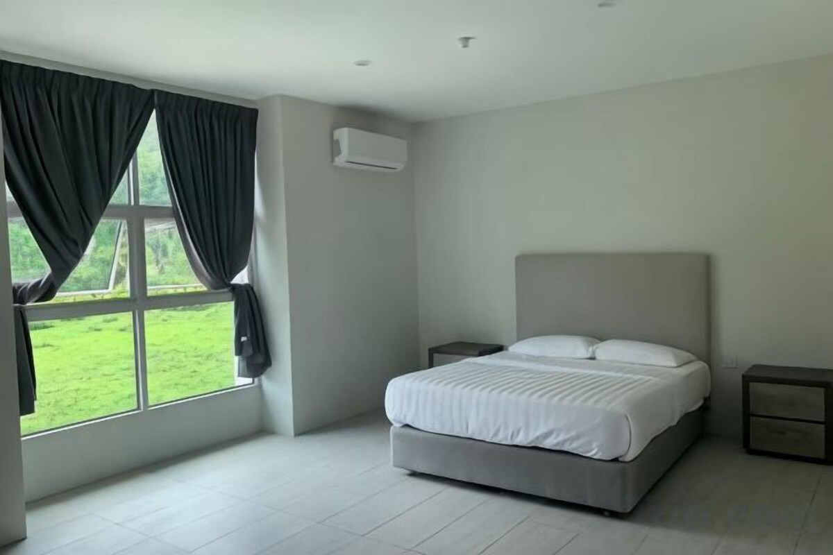 A bedroom with a bed, nightstands, a window with curtains, and a view of a green landscape.