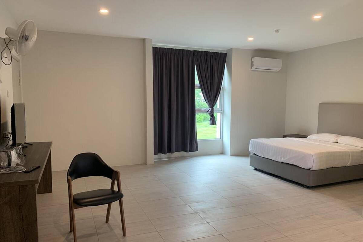 A hotel room with a desk, chair, bed, and a window with curtains.