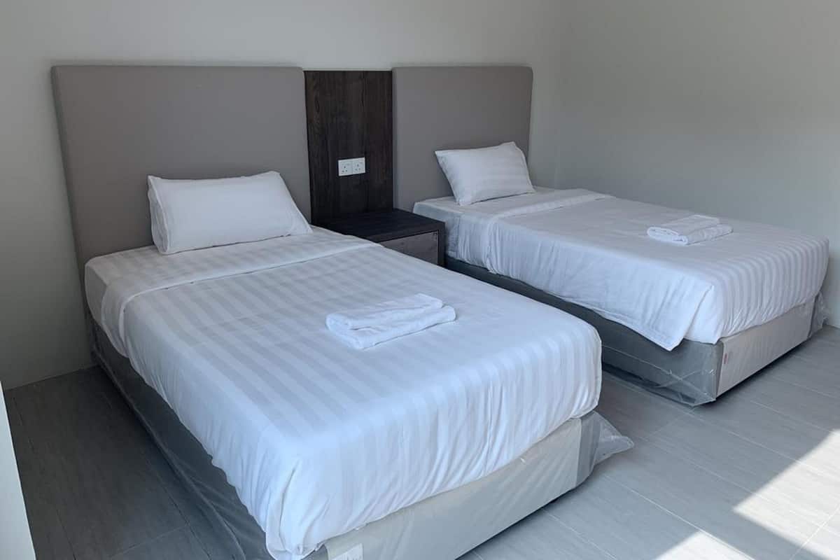 A hotel room with two beds, each with white linens and pillows, a wooden headboard, and a small nightstand between them.