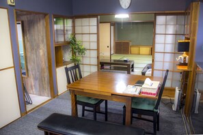 A traditional Japanese-style room with tatami flooring, a wooden table, and green cushions.