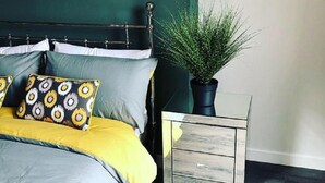 Un dormitorio con cama, mesita de noche y una planta en maceta.