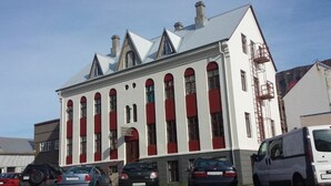 Ein großes, weißes Gebäude mit roten Fensterläden und einem weißen Lieferwagen davor.