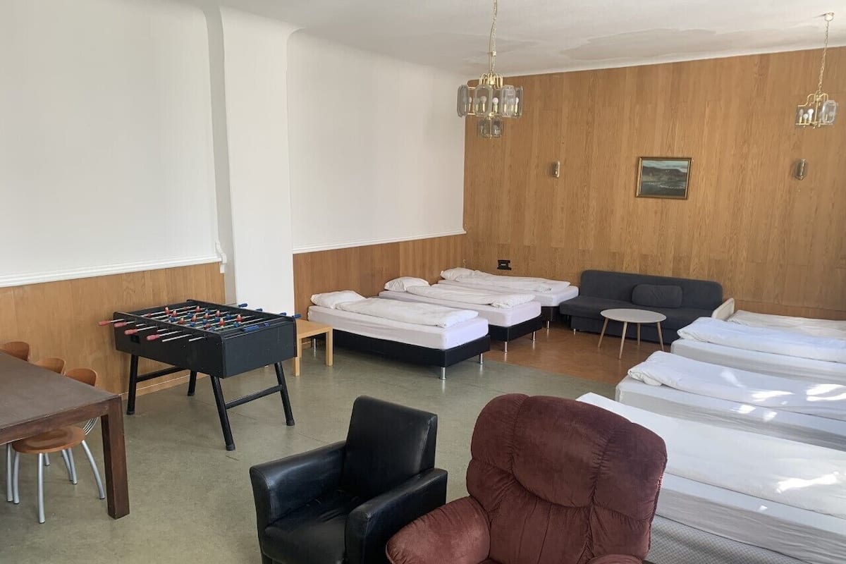 Une pièce avec une table de baby-foot, plusieurs lits, un canapé et un fauteuil.