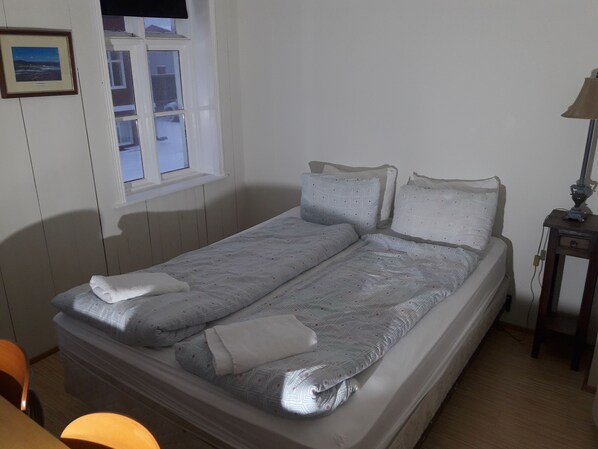 A single bed with a patterned duvet, pillows, and a bedside table with a lamp. - Mánagisting Guesthouse (Isafjordur)