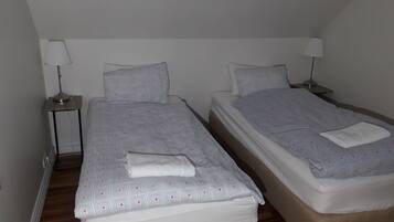 Habitación doble con dos camas individuales, cada una con almohada y lámpara de noche.