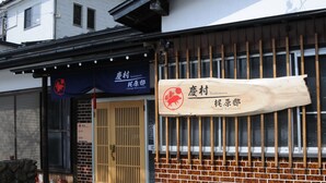Un bâtiment traditionnel japonais, avec une enseigne en bois et un auvent bleu.