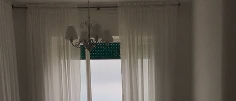Un dormitorio con cama, mesita de noche, lámpara y ventana con cortinas.