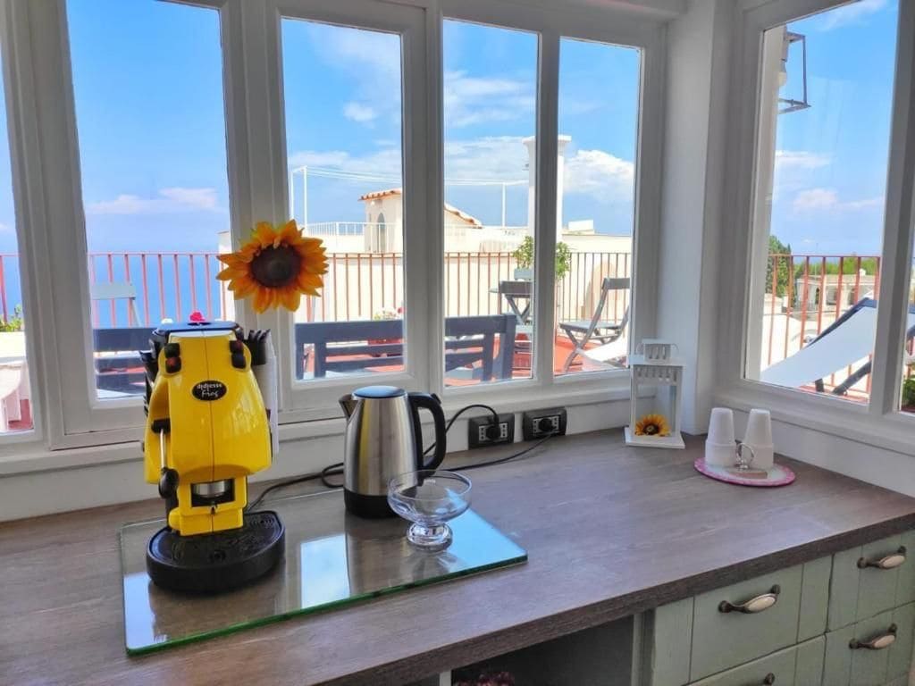 A kitchen counter with a coffee maker, a glass, and a sunflower decoration.