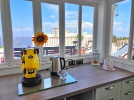 Eine Küchenarbeitsplatte mit Kaffeemaschine, einem Glas und einer Sonnenblumen-Dekoration.